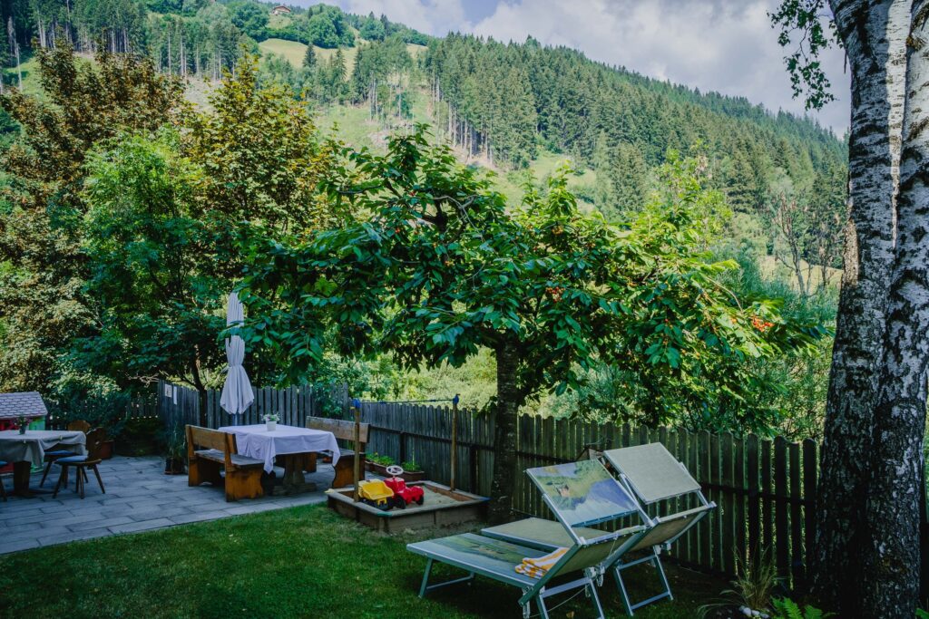 Hotelgarten Hotel Alpenblick, mit Liegestühlen und Bäumen